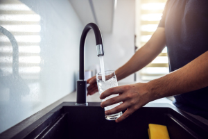 Person pouring fresh water from kitchen sink.