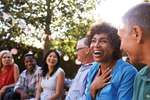 A diverse group of older adults sitting outdoors in a circle at a community gathering.